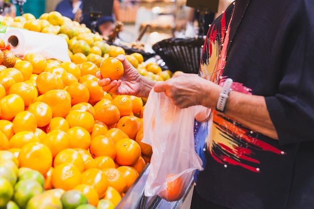 Donna anziana che compra arance al negozio di alimentari