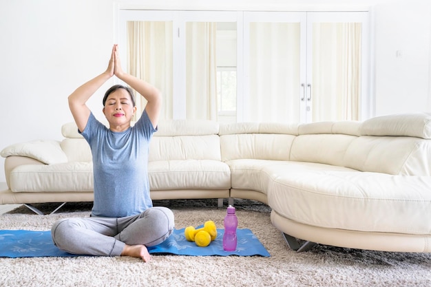 Donna anziana che fa esercizio di yoga a casa