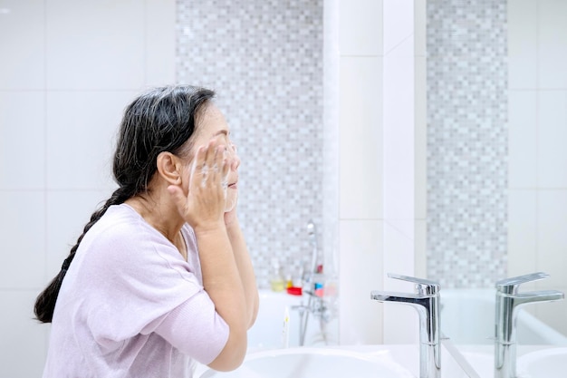 Donna anziana che fa il trattamento della pelle del viso a casa