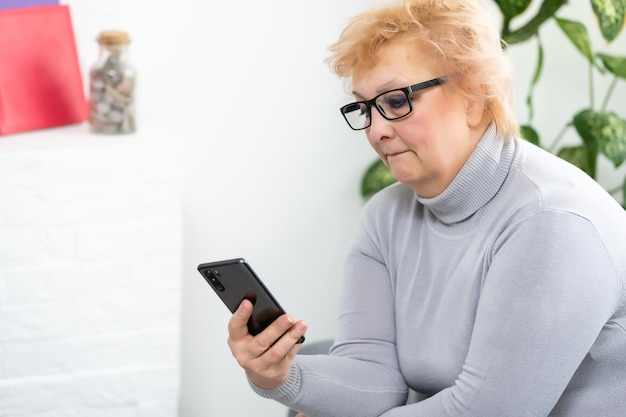 Donna anziana che fa telefonata a casa. Ritratto bello di donna matura sorridente che parla sullo smartphone, rilassante.