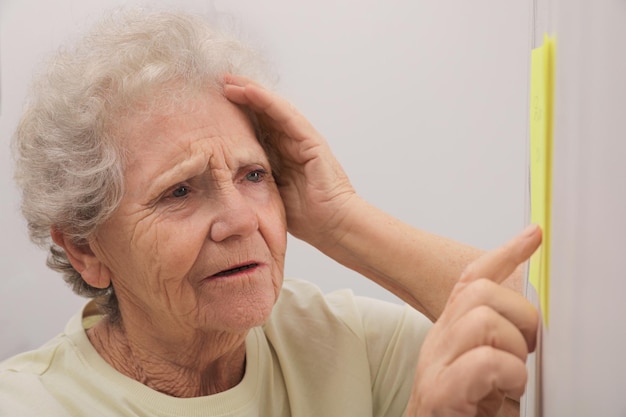 Donna anziana che guarda la nota di promemoria all'interno Compromissione della memoria legata all'età