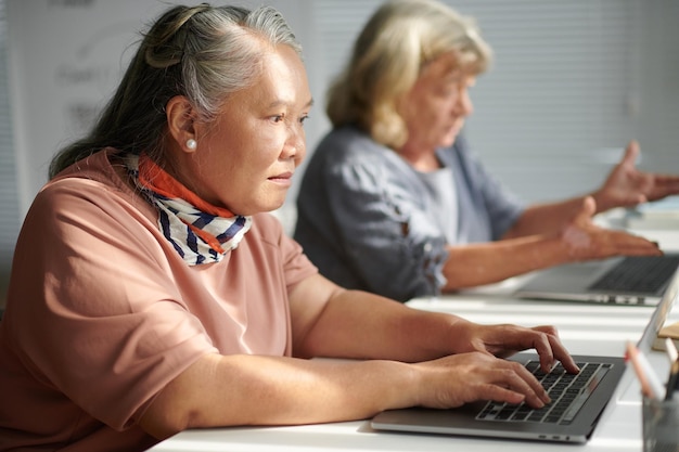 Donna anziana che lavora su un computer portatile in classe per anziani