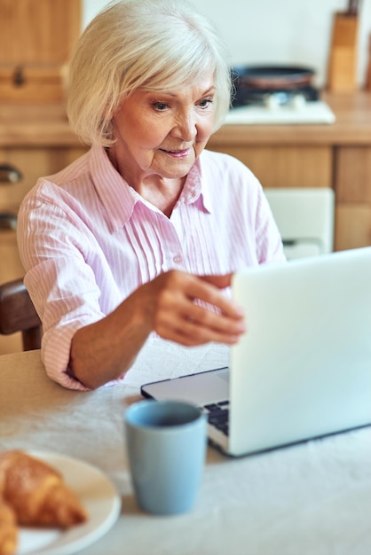 Donna anziana che legge notizie online a casa