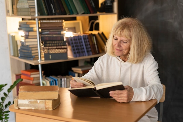 Donna anziana che legge un libro a casa