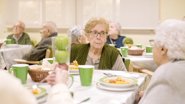 Donna anziana che mangia in una sala da pranzo di un geriatrico