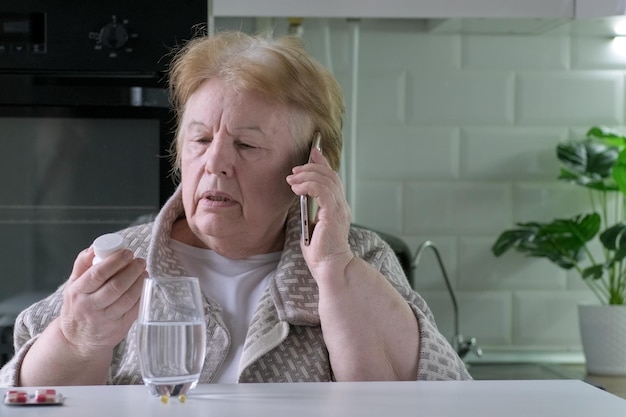 Donna anziana che parla al telefono cellulare con il medico sulla medicina in mano