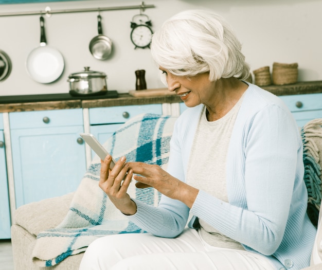 Donna anziana che per mezzo del telefono cellulare a casa