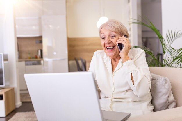 Donna anziana che riceve buone notizie al telefono urlando di felicità Donna matura eccitata urlando di gioia mentre parla al telefono e usa il portatile