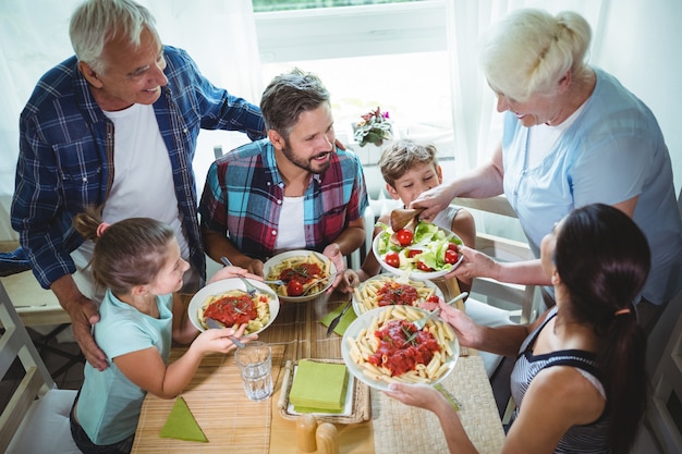 Donna anziana che serve pasto alla sua famiglia