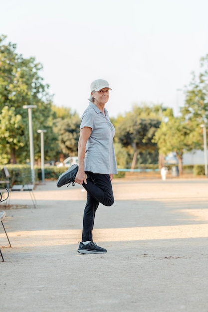 Donna anziana che si estende in un parco all'aperto