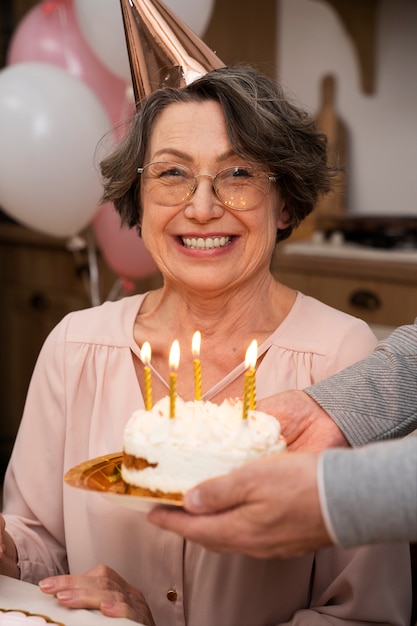 Donna anziana che soffia candele e si diverte alla festa