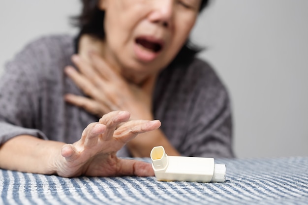 Donna anziana che soffoca e tiene in mano uno spray per l'asma