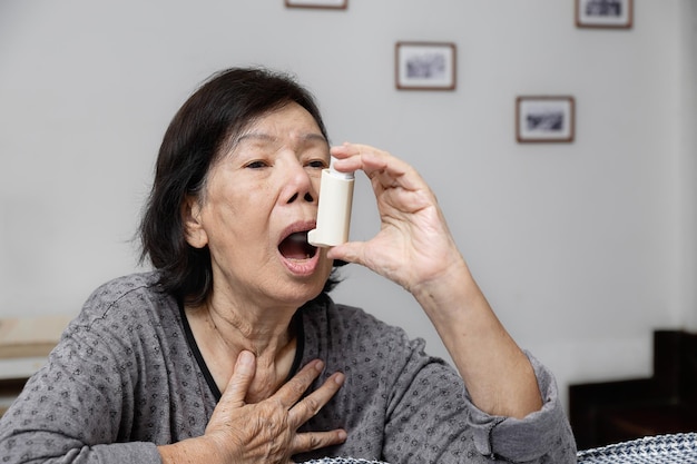 Donna anziana che soffoca e tiene in mano uno spray per l'asma
