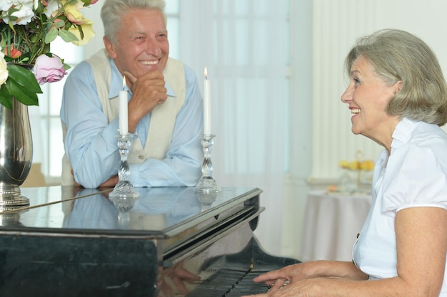 Donna anziana che suona il pianoforte a casa con suo marito