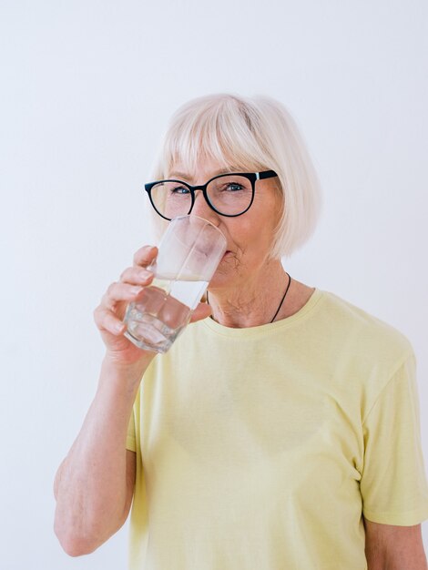 donna anziana che tiene in mano un bicchiere d'acqua e acqua potabile Stile di vita sano sport concetto anti età