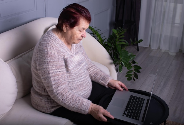 Donna anziana che usa un portatile sul tavolo a casa