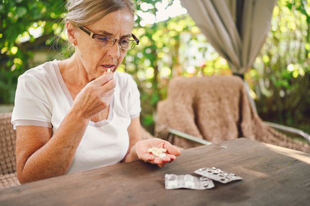 Donna anziana con gli occhiali che prendono le pillole