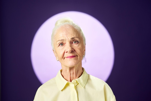 Donna anziana con i capelli bianchi che guarda l'obbiettivo contro la luna piena
