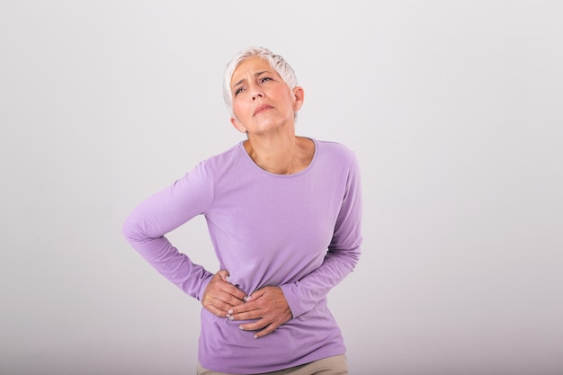 Donna anziana con i capelli grigi che tocca la sua anca dolorante. Sconvolta la donna anziana matura che tocca la schiena si sente ferita osteoartrite reni dolori muscolari doloranti