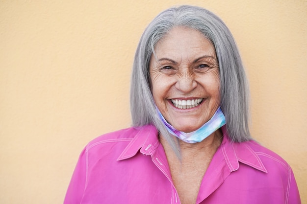 Donna anziana con maschera protettiva sotto il mento durante l'epidemia di coronavirus