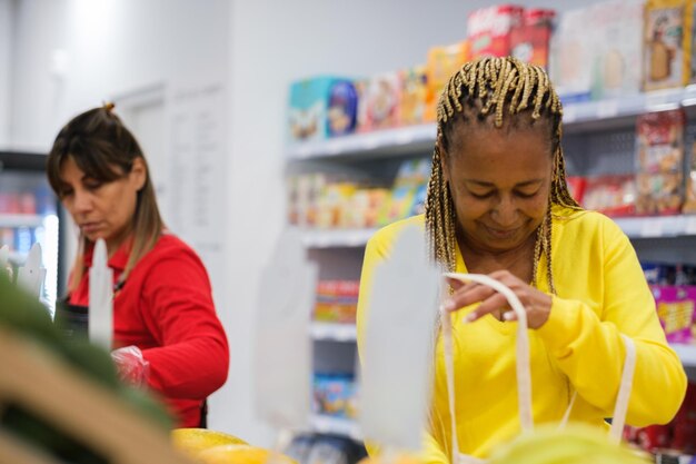 Donna anziana con trecce che mette frutta in borsa ecologica