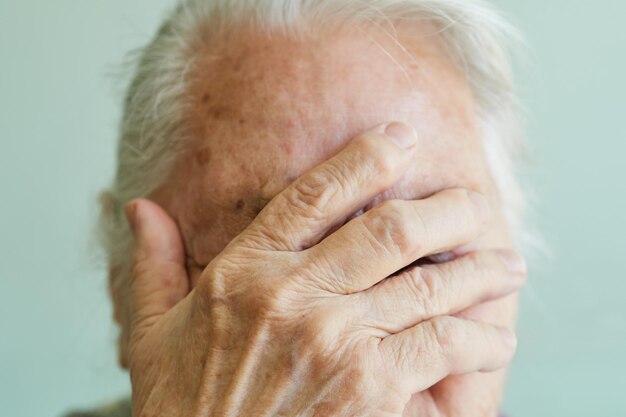 Donna anziana del primo piano che copre il viso con la mano