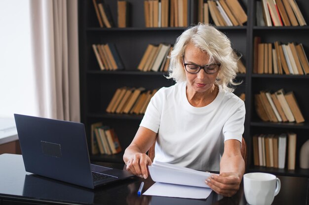 Donna anziana di mezza età con fiducia e stile che usa il portatile sul posto di lavoro donna d'affari più anziana e matura