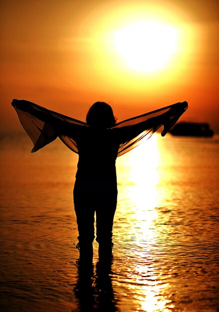 Donna anziana felice al tramonto in spiaggia