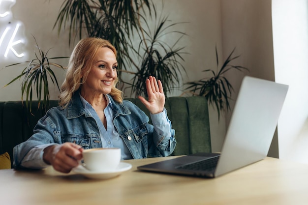 Donna anziana felice che si diverte a fare videochiamate utilizzando il laptop nella caffetteria Videochiamata Comunicazione