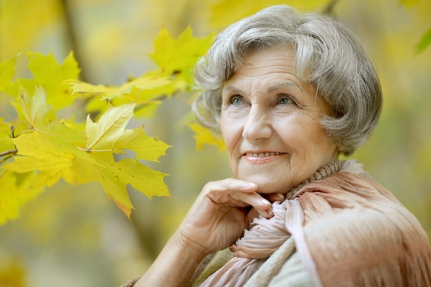 Donna anziana felice che si gode nel parco autunnale