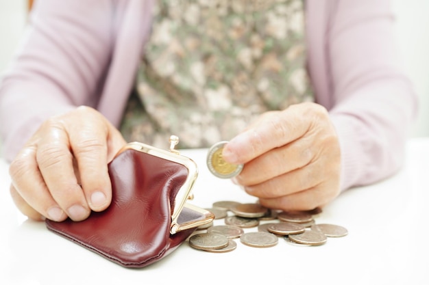 Donna anziana in pensione che conta le monete e si preoccupa delle spese mensili e delle spese di trattamento