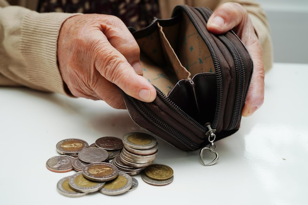 Donna anziana in pensione che conta monete denaro e si preoccupa delle spese mensili e del pagamento della quota di trattamento