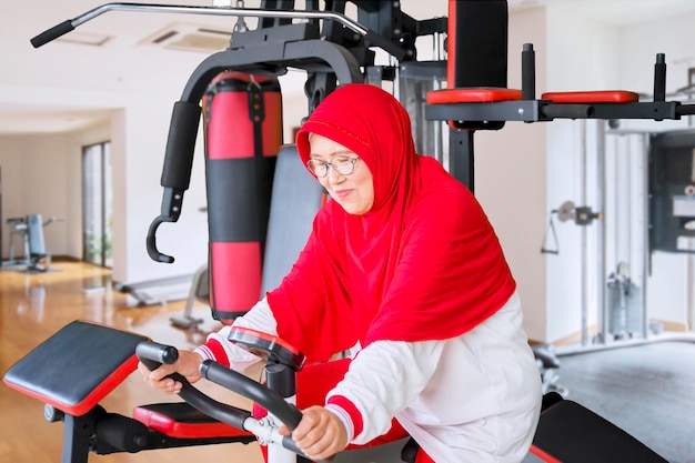 Donna anziana musulmana che fa allenamento sulla macchina da palestra