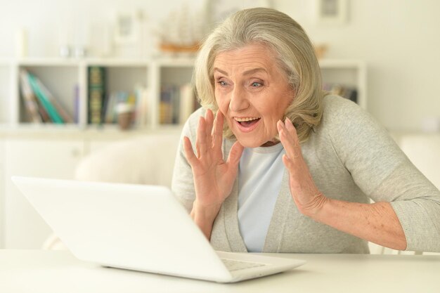 donna anziana seduta al tavolo con il computer portatile