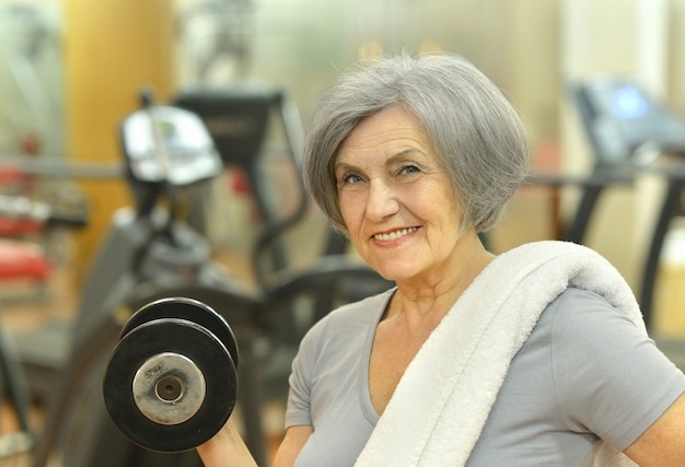 Donna anziana sorridente carina che si esercita in palestra