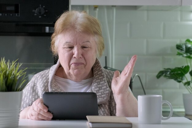 Donna anziana sorridente felice con computer tablet digitale con videochiamata a casa