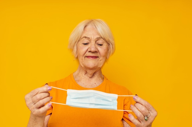 Donna anziana sorridente in magliette gialle in maschere mediche emozioni di primo piano