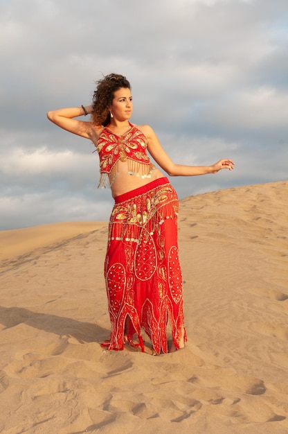 Donna araba che balla la danza del ventre tra le dune del deserto al tramonto