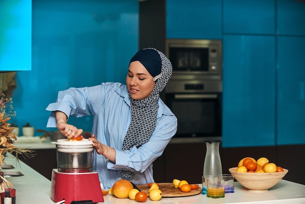 Donna araba hijab che produce succo di frutta in cucina moderna Concetto di casa Concetto di stile di vita sano Messa a fuoco selettiva Foto di alta qualità