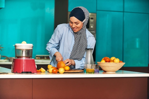 Donna araba hijab che produce succo di frutta in cucina moderna Concetto di casa Concetto di stile di vita sano Messa a fuoco selettiva Foto di alta qualità
