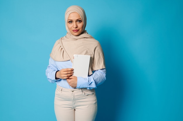 Donna araba musulmana seria e serena con un libro bianco tra le mani. Concetti di educazione