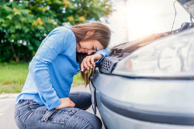 Donna arrabbiata che reagisce emotivamente alla macchina surriscaldata. L&#39;auto in piedi in disparte.