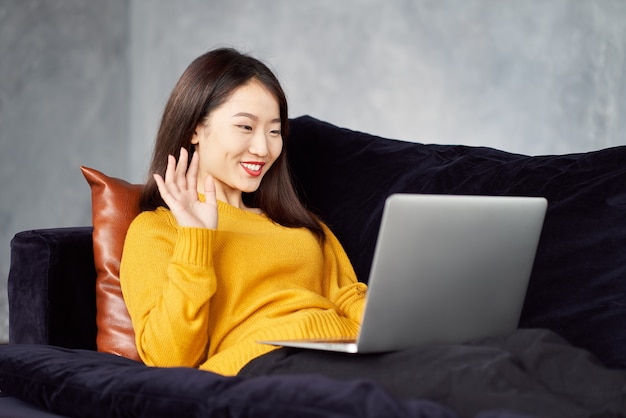 Donna asiatica agitando le mani cercando di laptop. Incontri online, incontri con gli amici