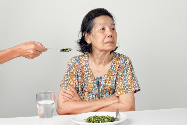 Donna asiatica anziana annoiata con il cibo