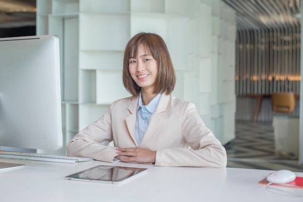 Donna asiatica attraente di affari che lavora al computer nel posto di lavoro