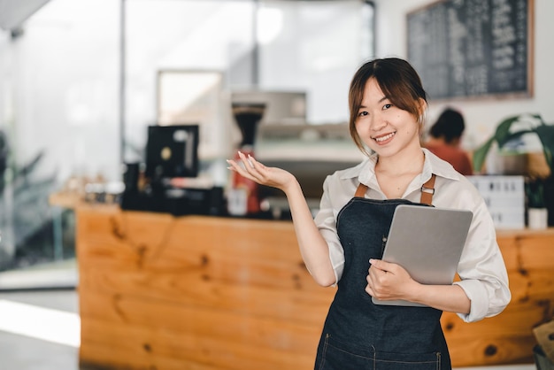 Donna asiatica barista in possesso di tablet digitale per il controllo dell'ordine dal cliente al bar caffetteria sfondo Concetto di business delle PMI