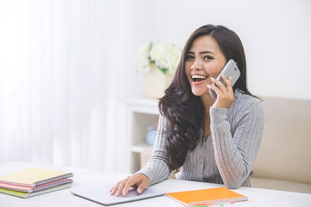 Donna asiatica casuale che fa una telefonata a casa facendo uso dello Smart Phone