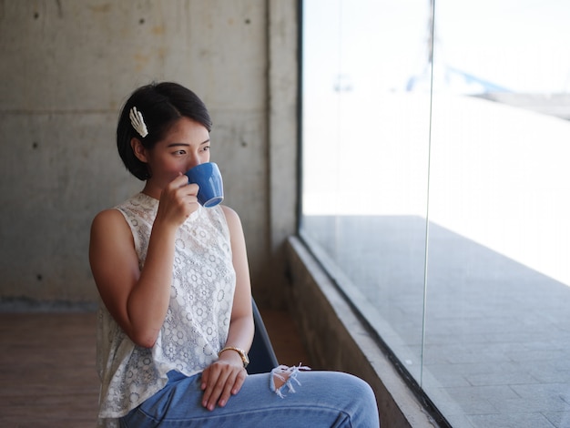 Donna asiatica che beve caffè nella caffetteria