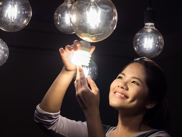 Donna asiatica che cambia lampadina