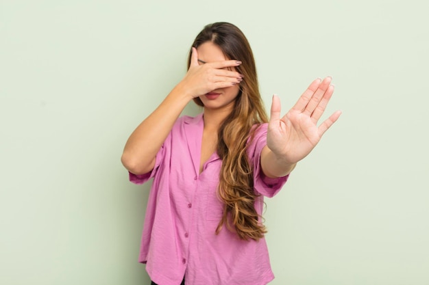 Donna asiatica che copre il viso con la mano e mette l'altra mano davanti per impedire alla fotocamera di rifiutare foto o immagini